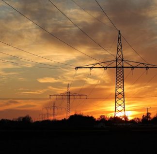 Torre de transmissão de energia com pôr do sol ao fundo.