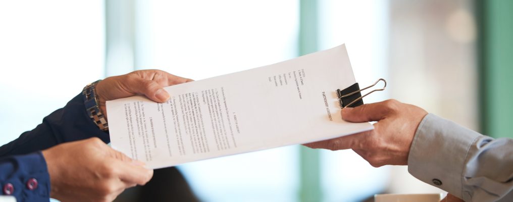 Business person giving partnership agreement to coworker