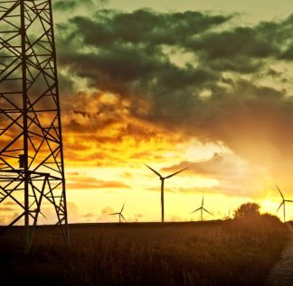 Torre de transmissão de energia com usina eólica ao fundo representando o curtailment